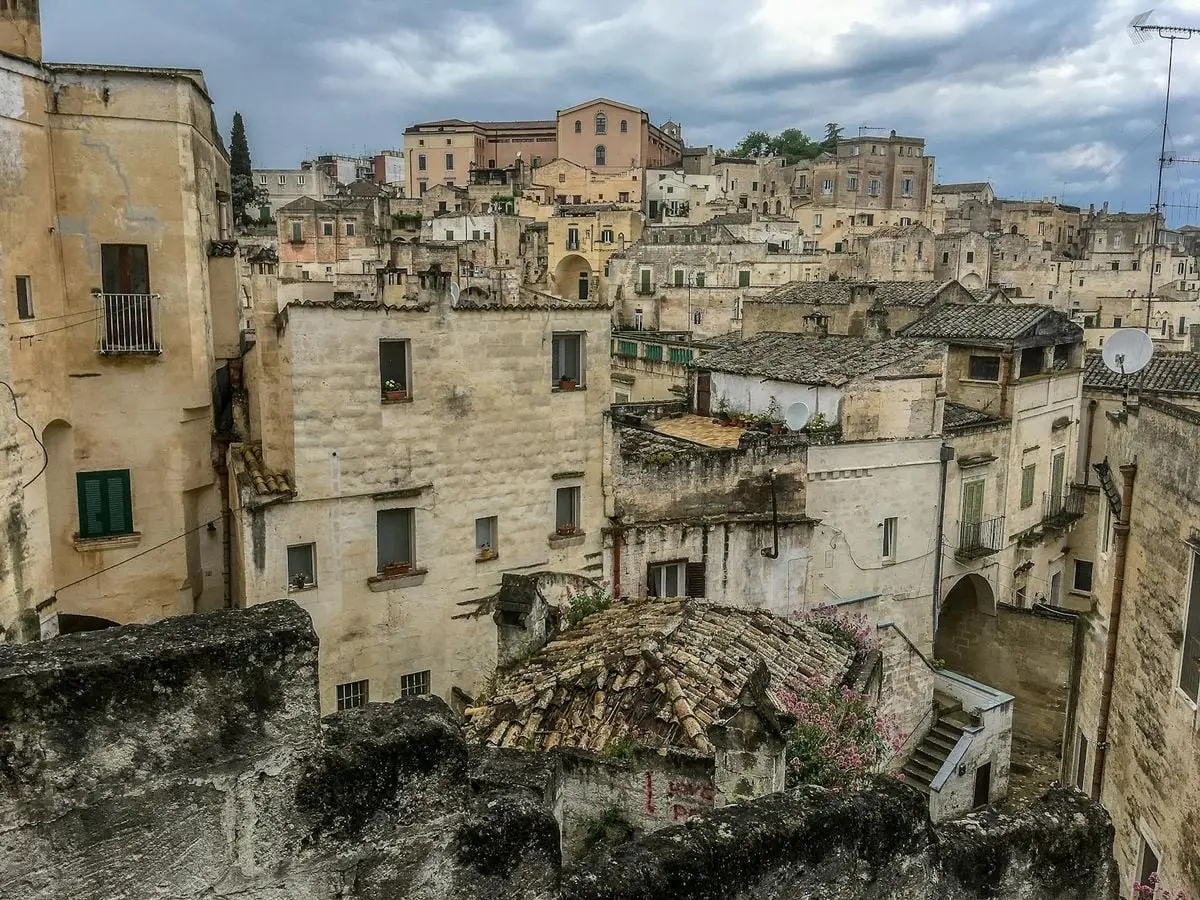 View of ancient stone buildings in Matera, Italy, under a cloudy sky showcasing historic architecture.