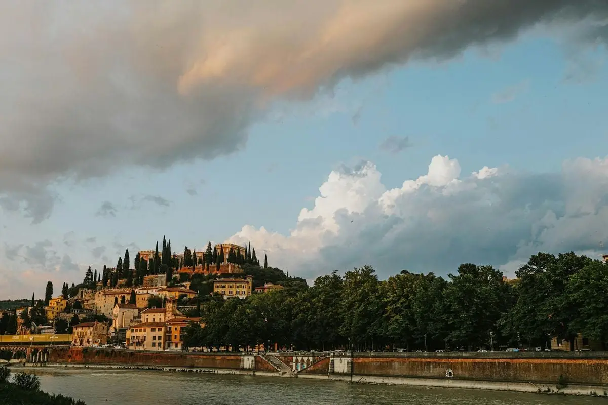 Beautiful Italian old town overlooking a river at sunset with vibrant clouds and rich greenery.