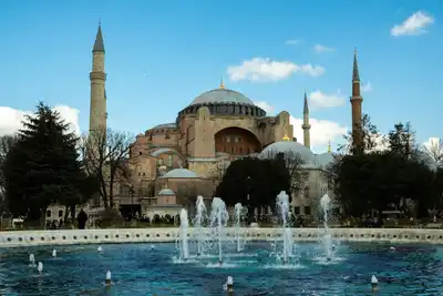 View of Hagia Sophia and a water fountain under a clear blue sky in Istanbul, Turkey.