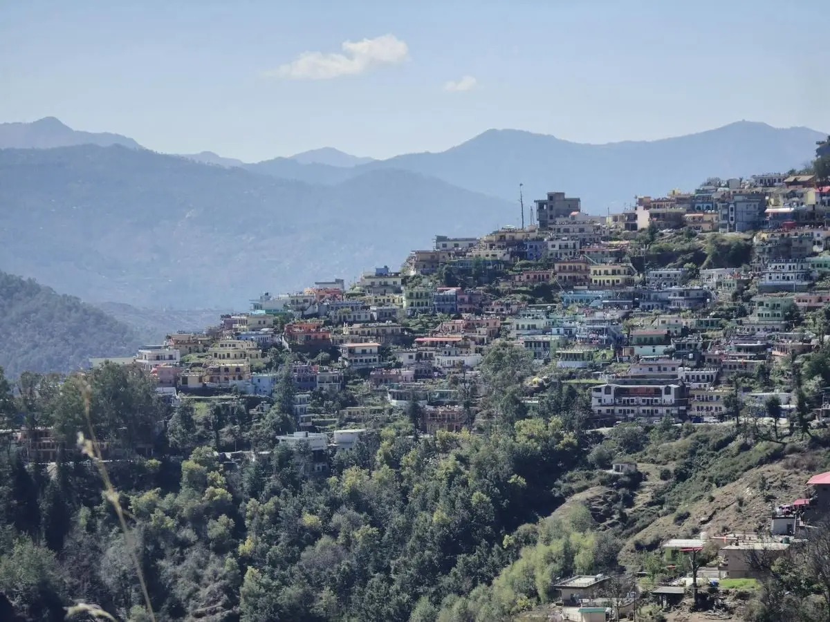 Scenic view of vibrant houses nestled on a hillside in Almora, India surrounded by mountains.