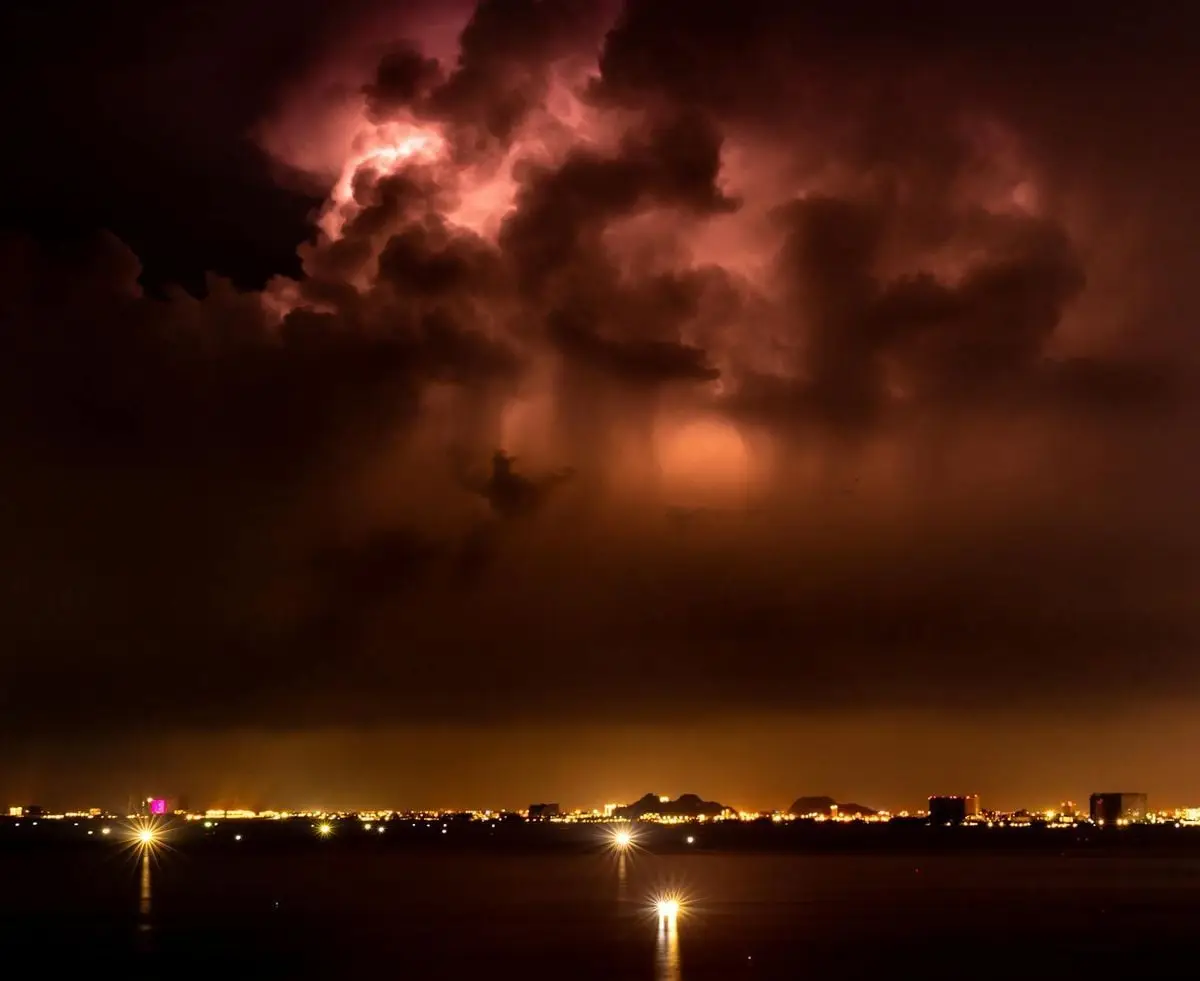 Captivating thunderstorm illuminates the night sky above a vibrant city skyline.