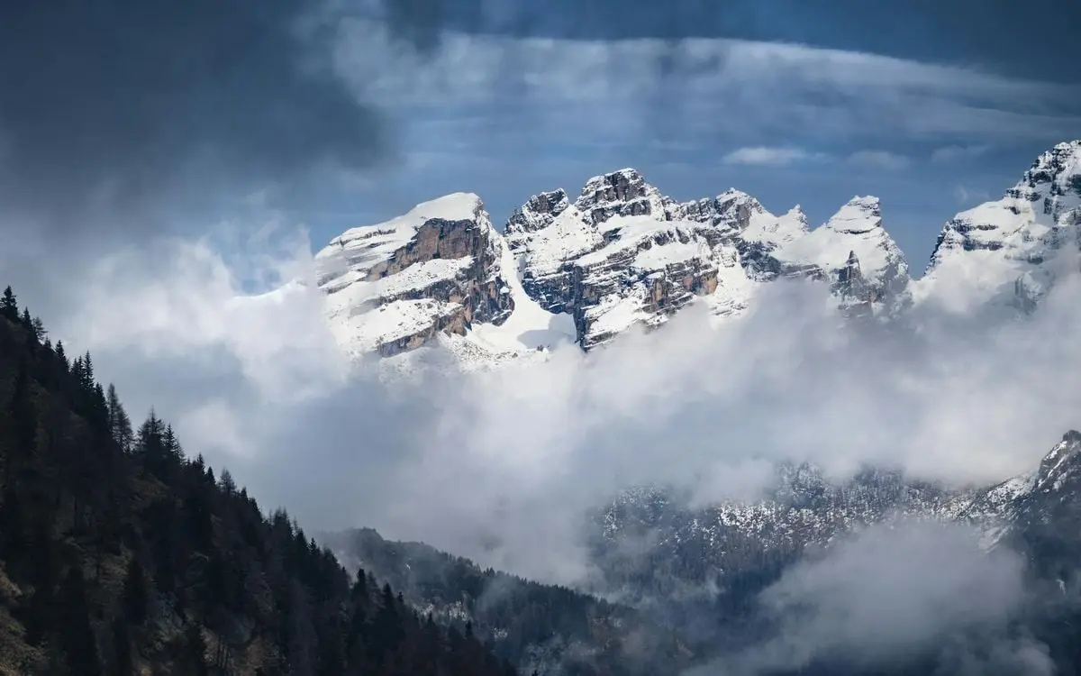 Experience the breathtaking beauty of snow-capped Alpine peaks surrounded by clouds and fog.