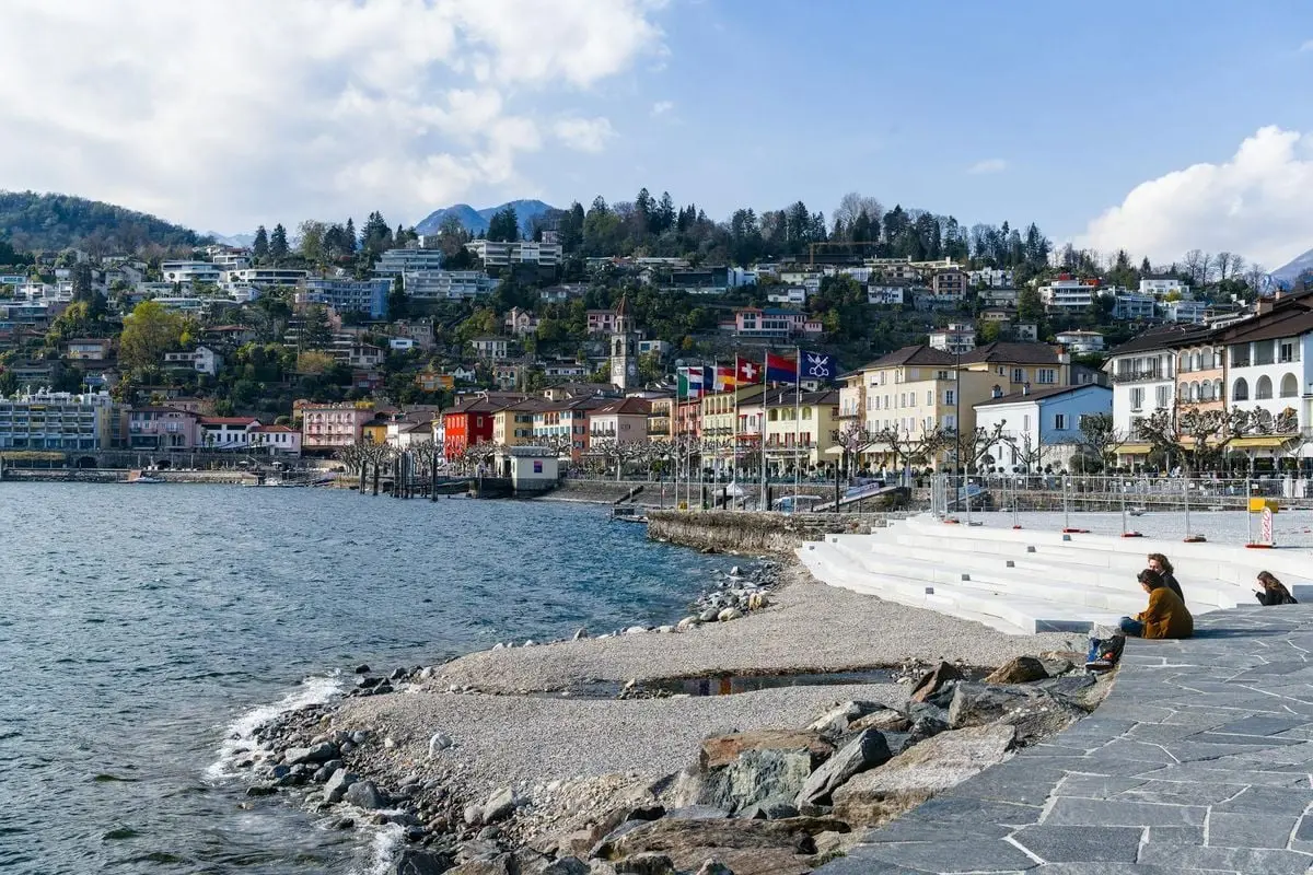 Scenic view of Ascona's stunning lakefront with colorful buildings and mountains.
