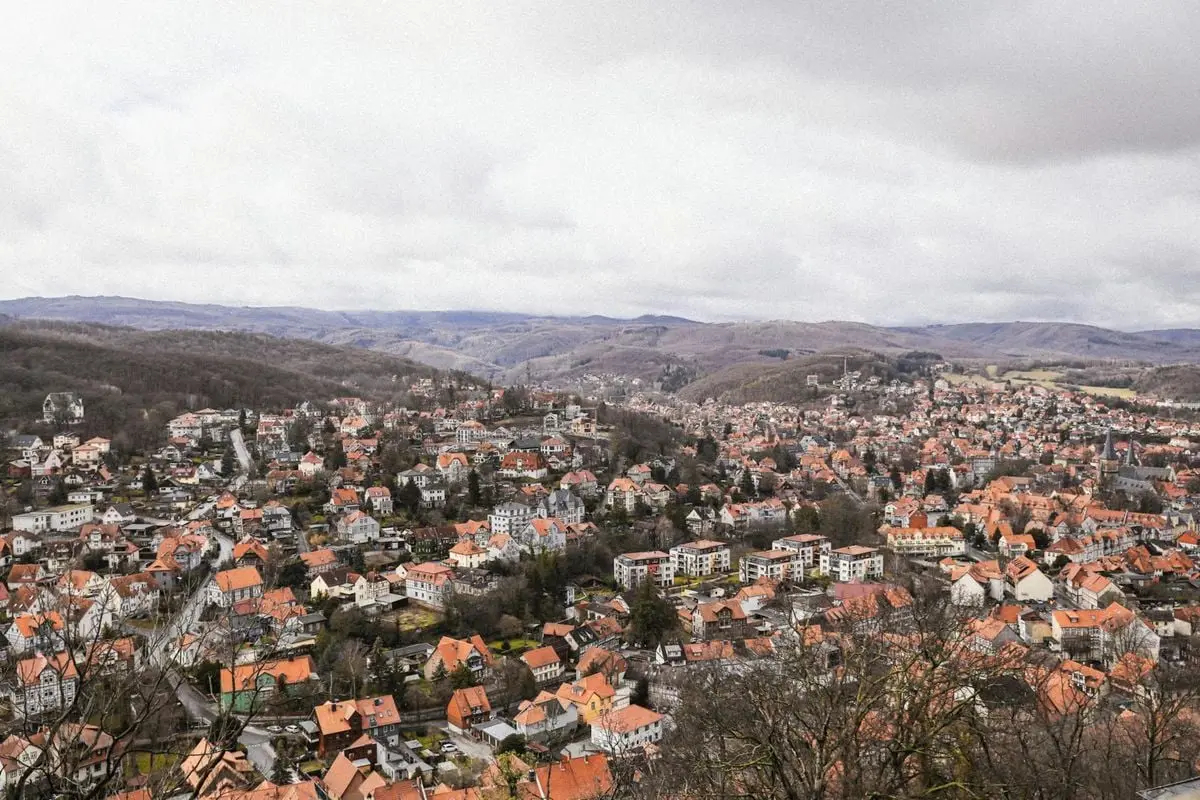 Elevated cityscape showcasing a European town surrounded by hills and under a cloudy sky.