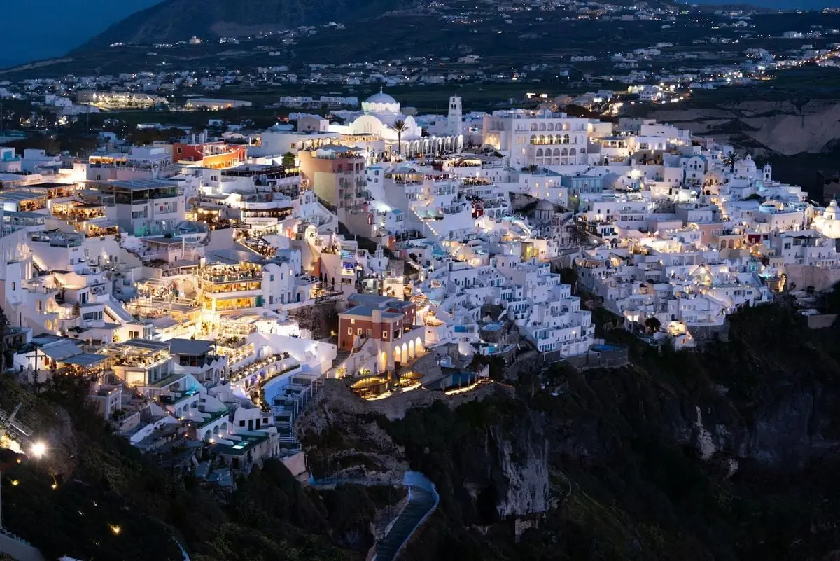 A mesmerizing aerial view of Santorini's illuminated white houses at night.