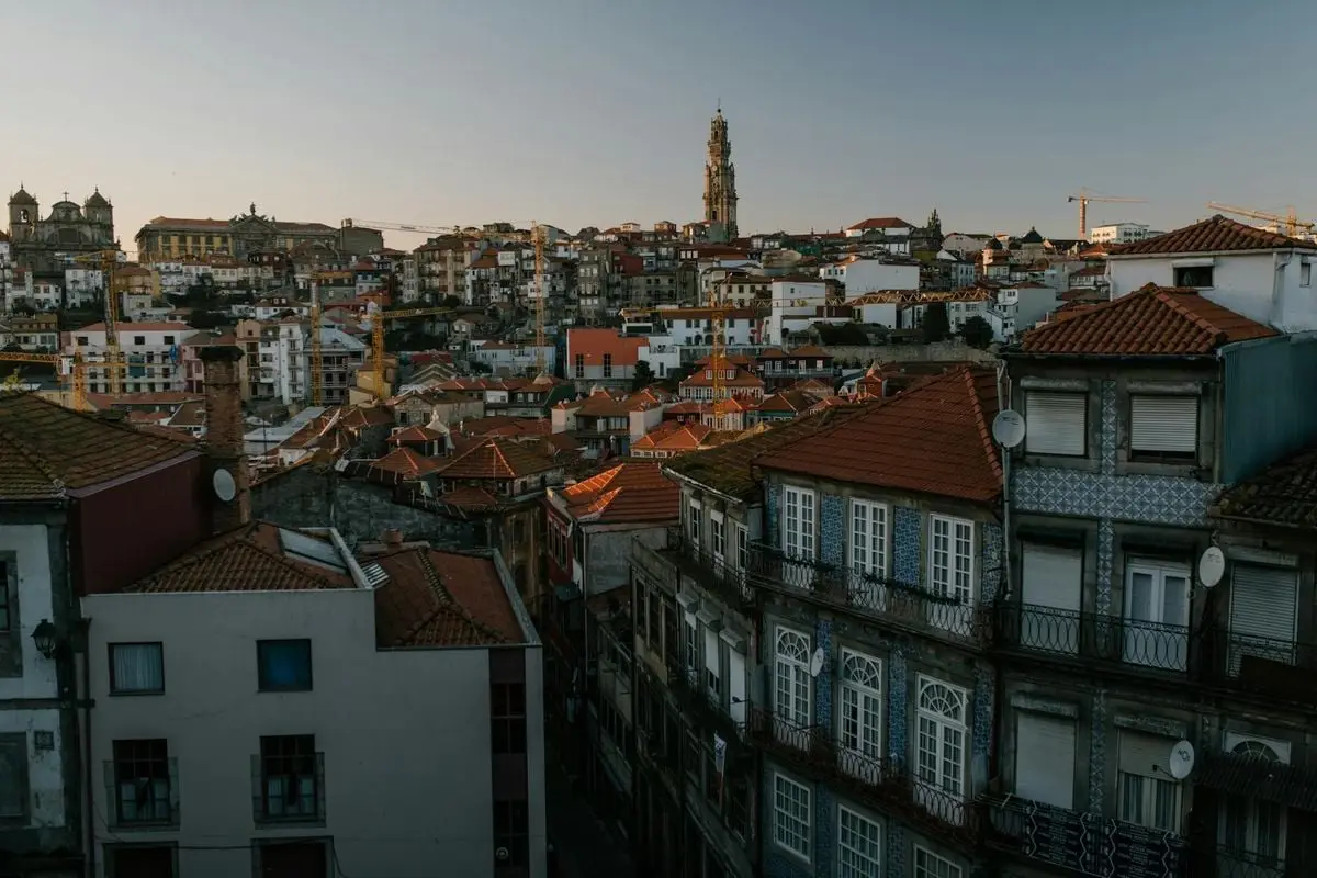Dramatic aerial view of Porto's historic cityscape with red roofs and iconic architecture at dusk.