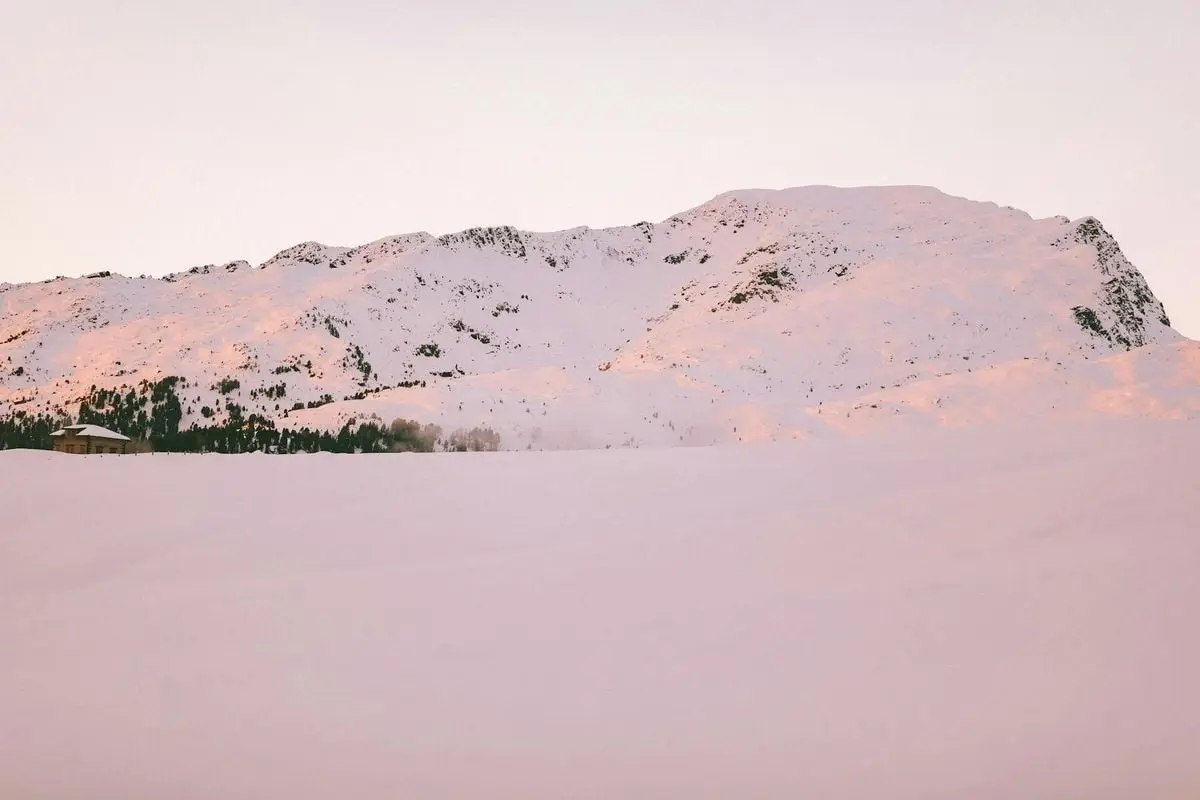 A serene snow-covered mountain landscape at sunrise, showcasing nature's tranquility.