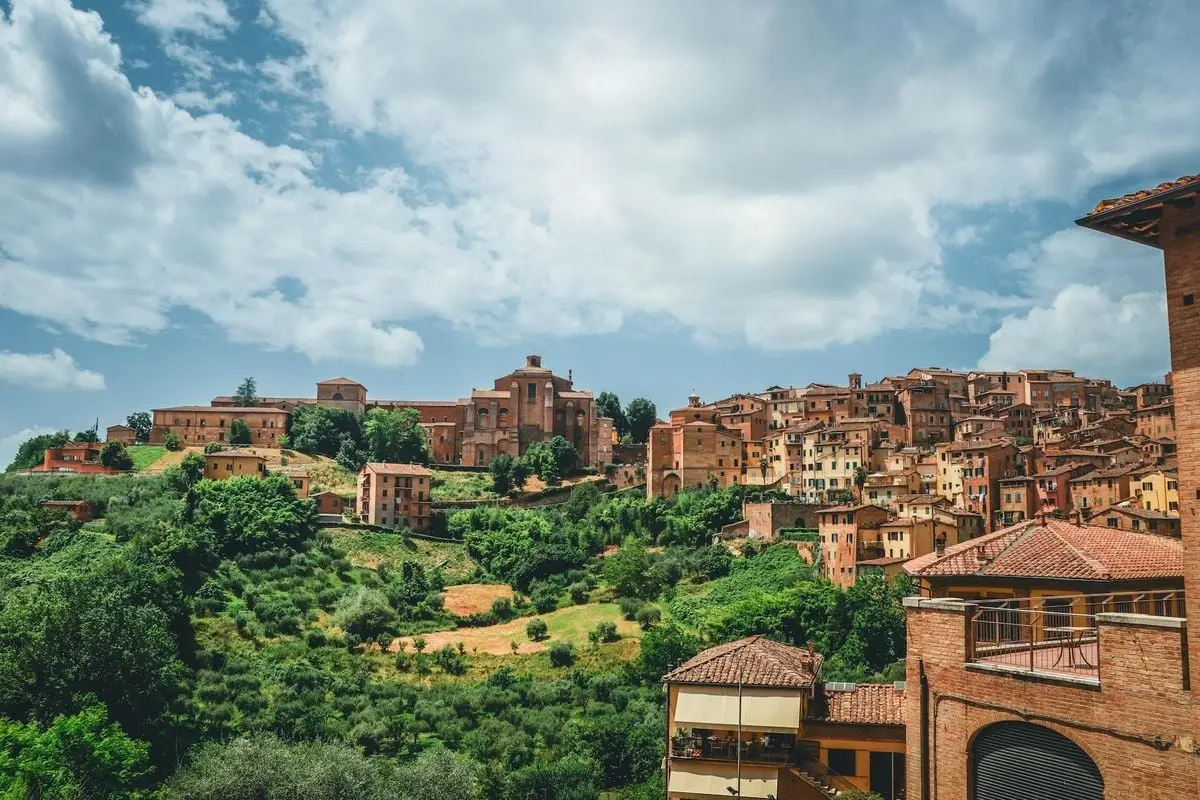 Explore the stunning architecture and lush greenery of San Gimignano, Tuscany under a bright sky.