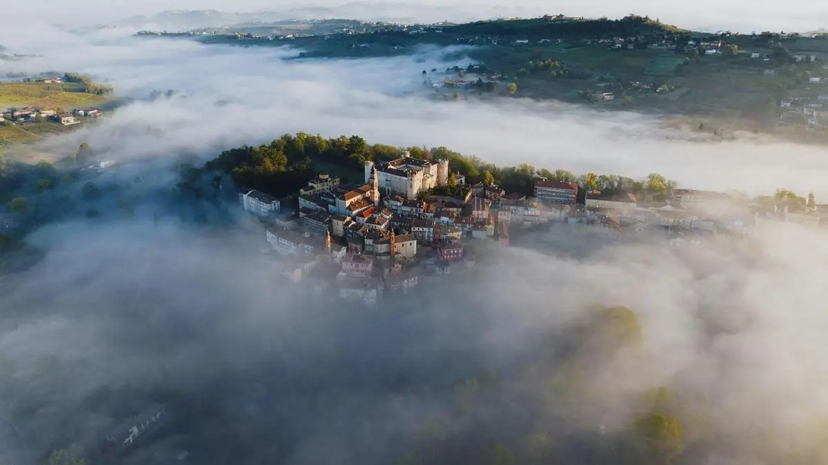 Stunning aerial view of Costigliole d'Asti, Italy, enveloped in morning fog, capturing the serene landscape.