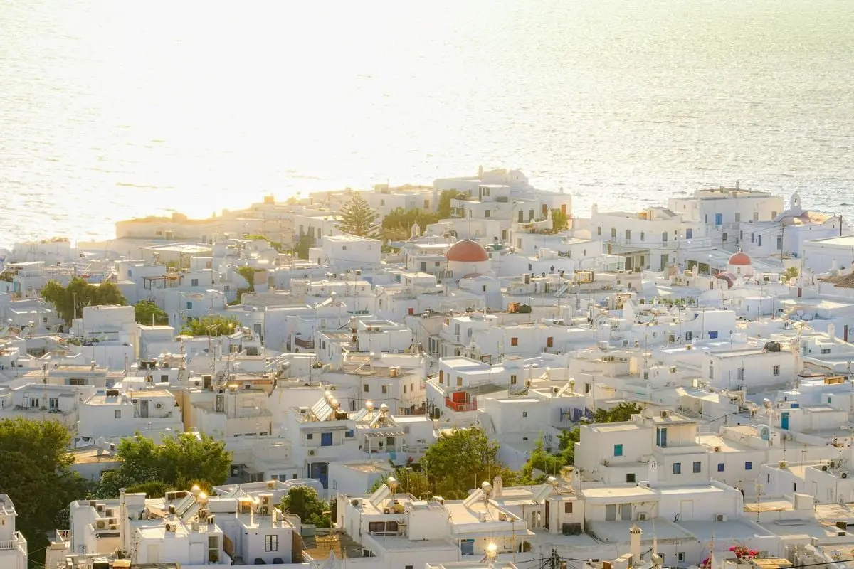 A picturesque view of Mykonos town with white buildings and sea at sunset.