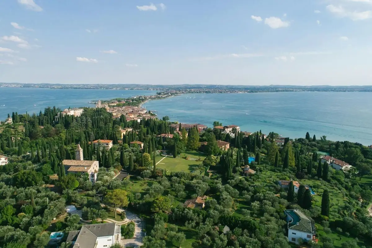 A lush aerial view of a picturesque lakeside town in Italy, surrounded by greenery and the serene lake waters.
