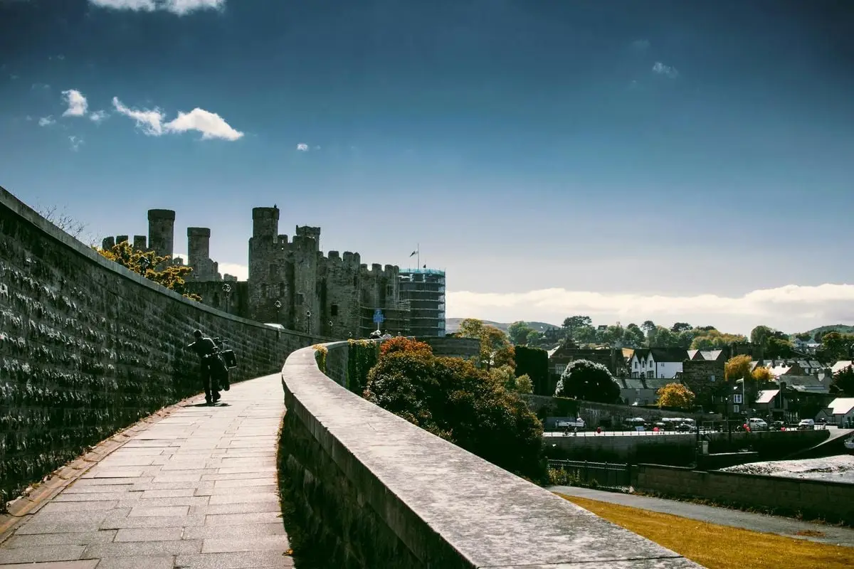 Explore the historic Conwy Castle and town walls under a bright, sunny sky in Conwy, Wales.