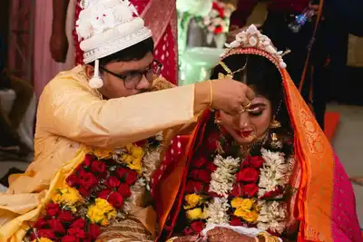A beautiful Indian couple in traditional attire during a wedding ceremony, adorned with colorful garlands.