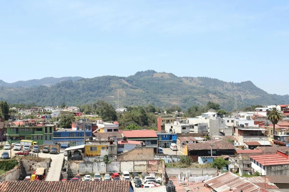 Aerial shot capturing vibrant rooftops and distant hills under a clear sky.