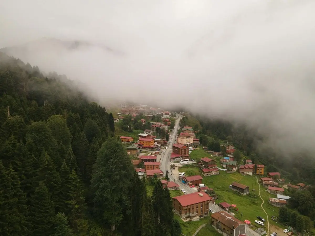 Aerial view of a foggy village surrounded by green forests in Rize, Turkey.