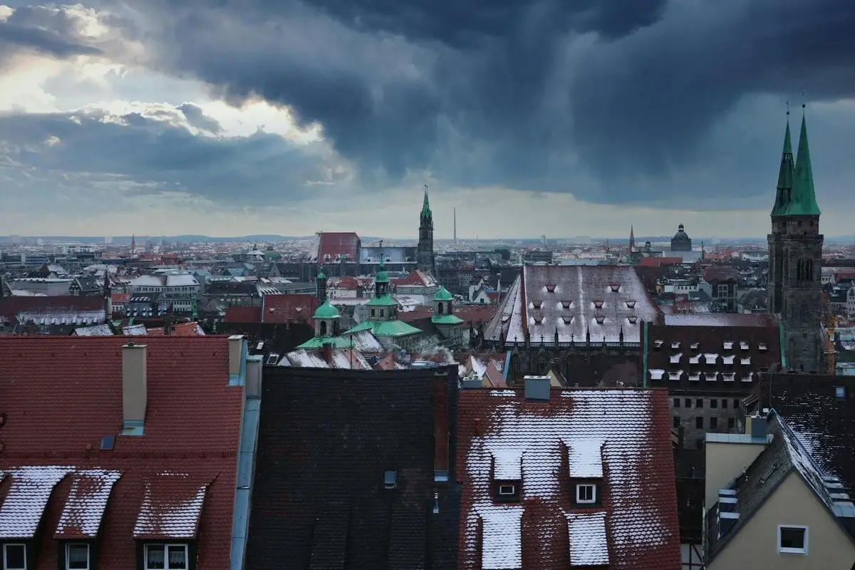 Winter cityscape of Nuremberg with snow-covered rooftops and a dramatic sky.