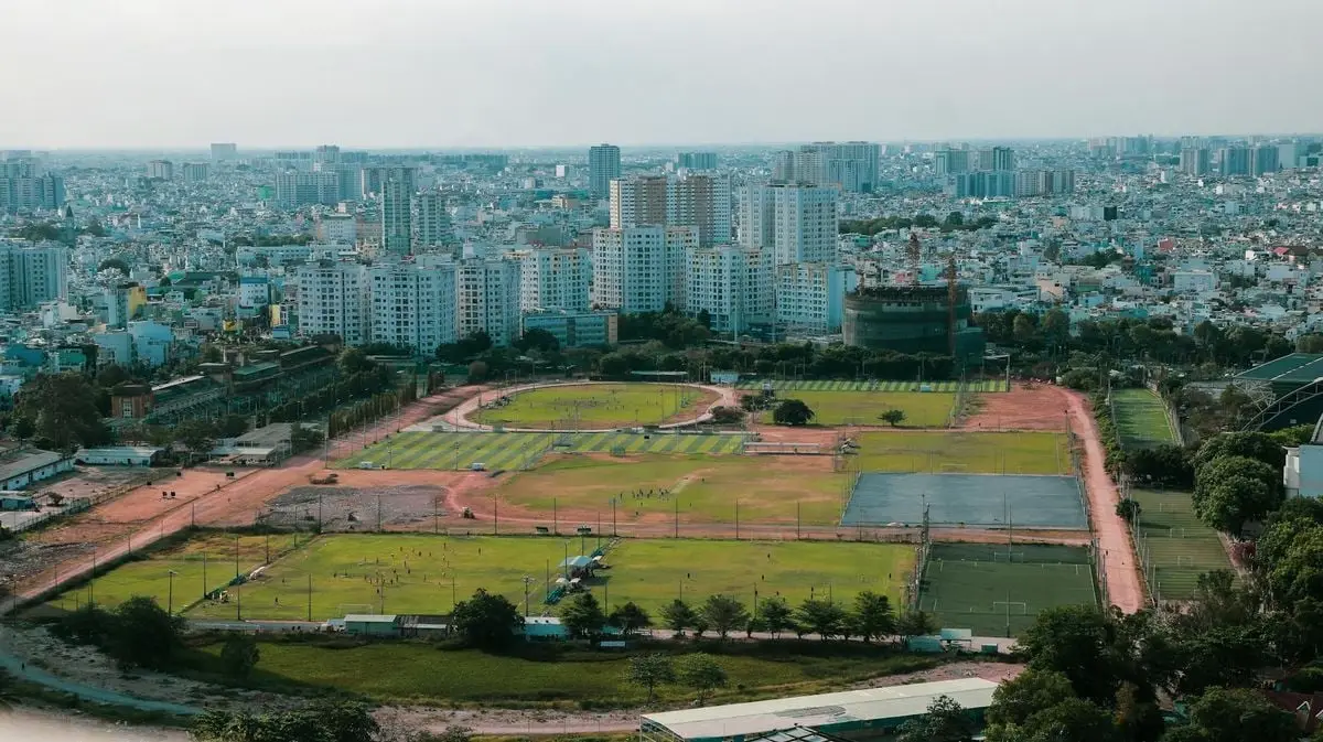Aerial view of urban cityscape with sports fields and skyscrapers under daylight.
