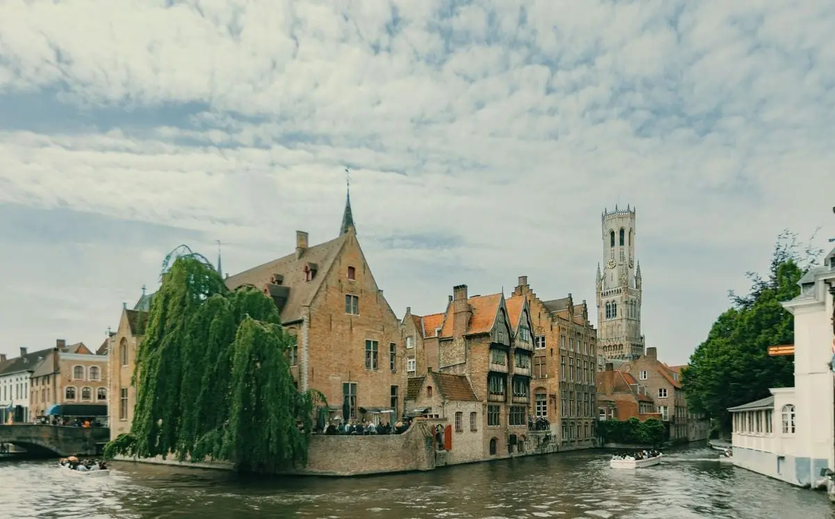 Historic buildings and canal with the Belfry of Bruges in view.