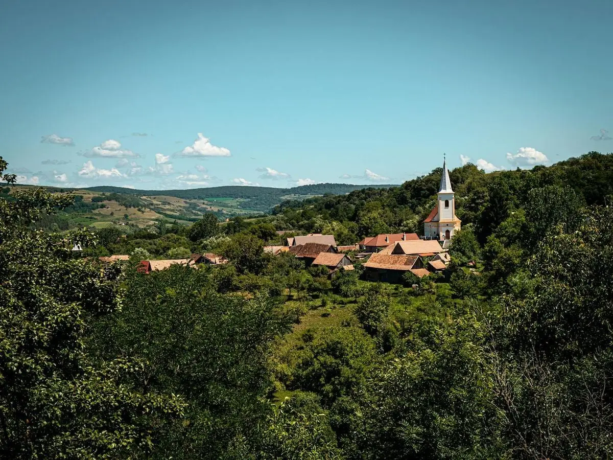 Charming village near Sibiu, Romania with lush green landscape and historic church tower.