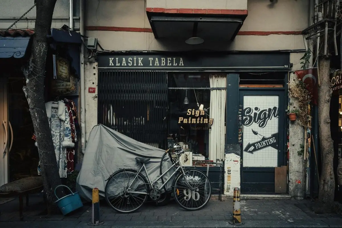 A vintage bicycle parked in front of a classic signage shop on an Istanbul street.
