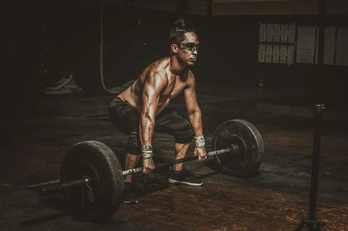A dedicated man performs a deadlift exercise in a dimly lit gym.