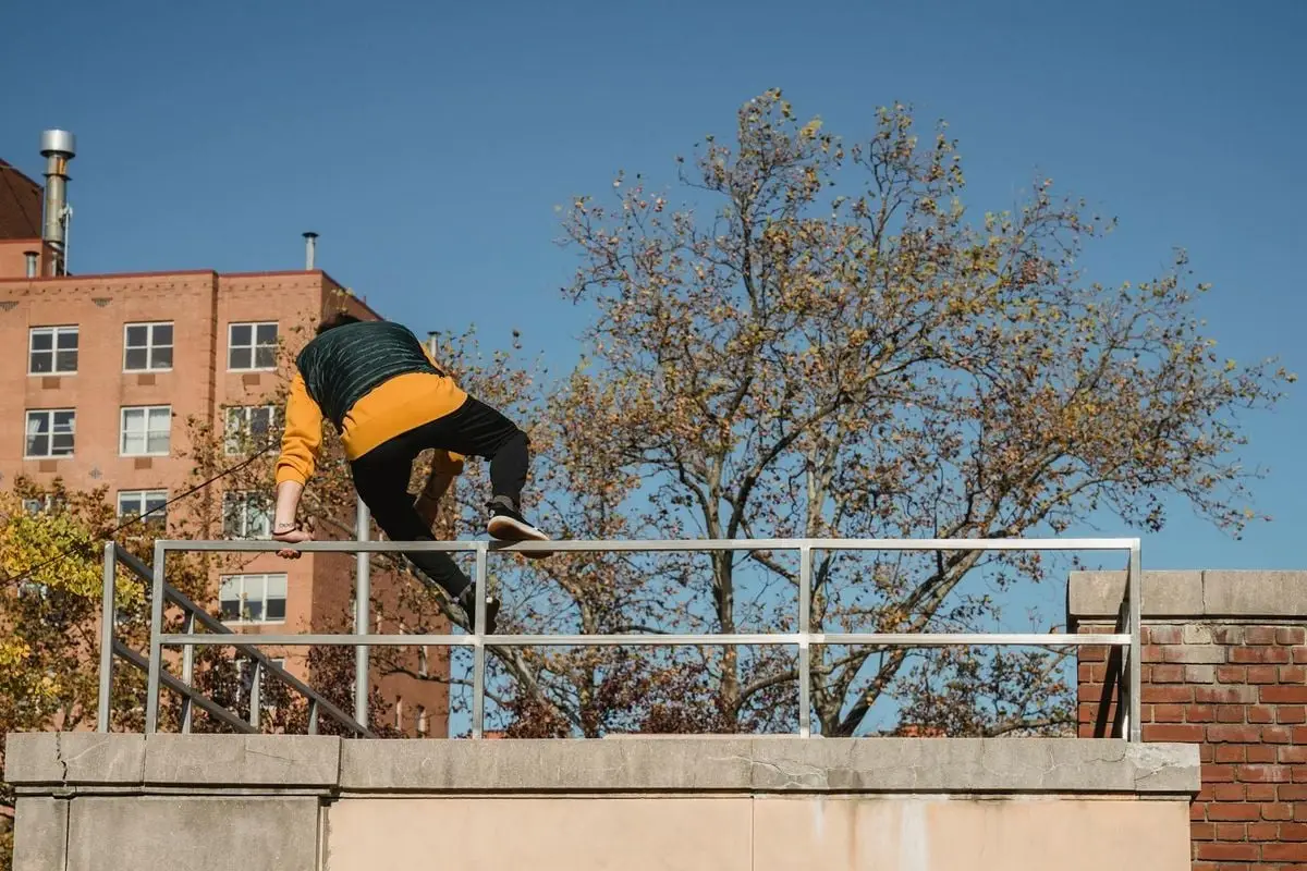 Back view of faceless male in activewear performing trick while practicing on height