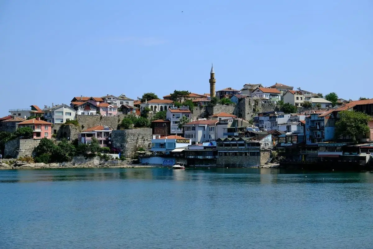 Charming Turkish town by the sea with traditional architecture and a minaret on a sunny day.