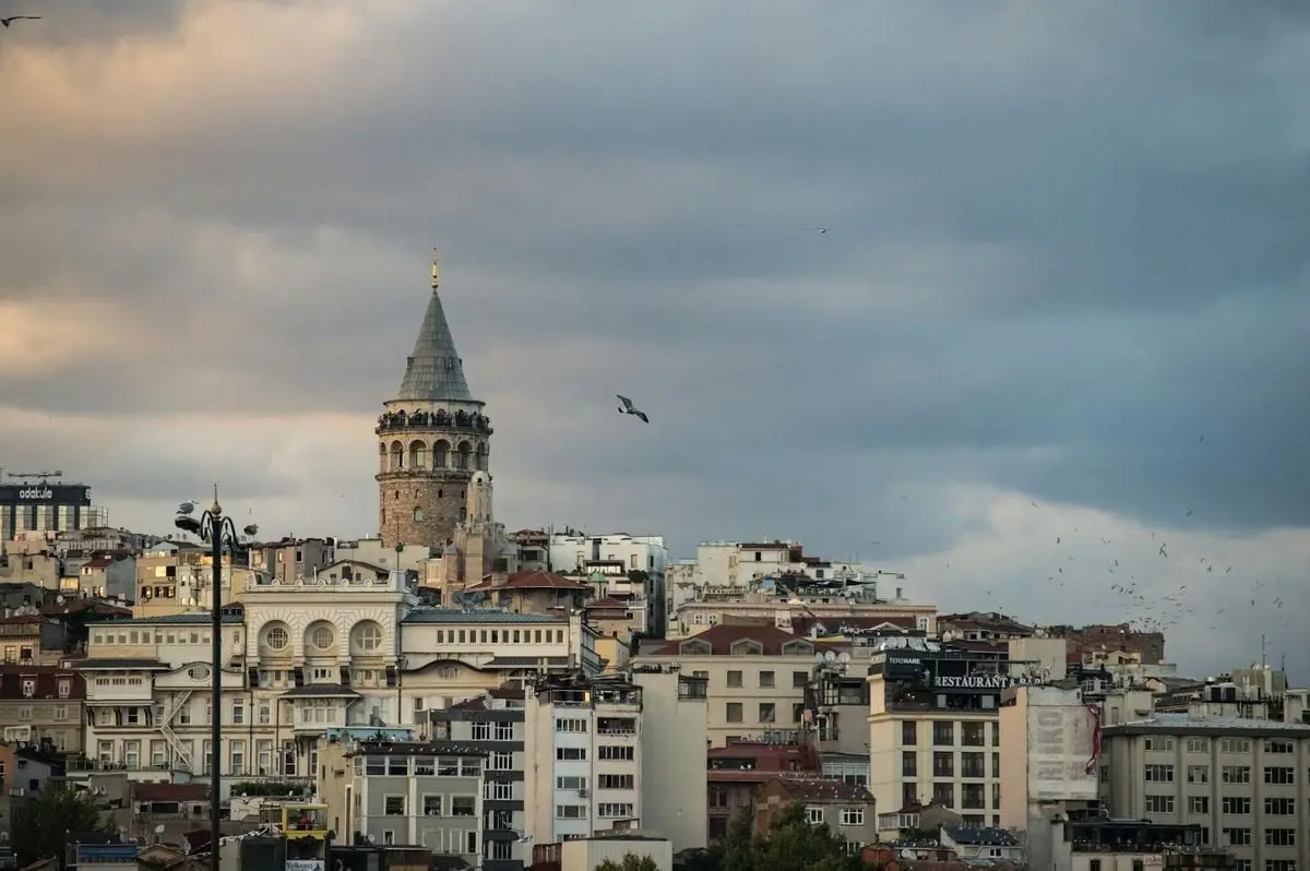 Aerial view of Galata Tower surrounded by Istanbul's urban skyline under an overcast sky.