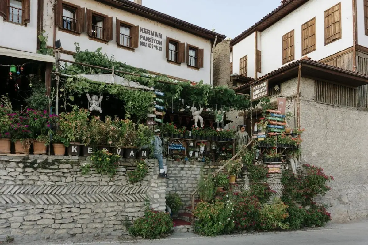 A picturesque view of a traditional Turkish guesthouse with lush greenery and vibrant flowers.