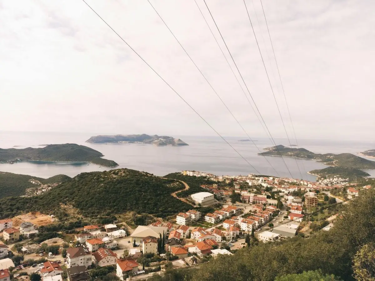 A breathtaking aerial view of a coastal city with distant islands under a cloudy sky.