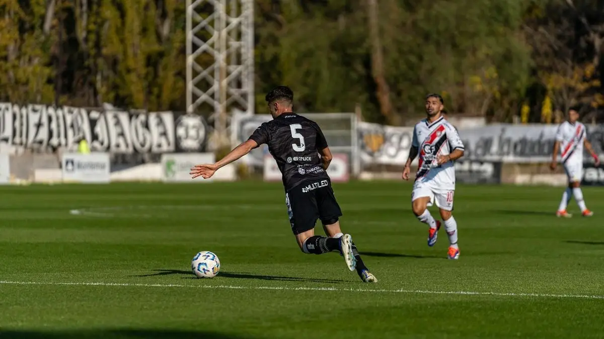 Football player in action kicking a ball during a match outdoors.