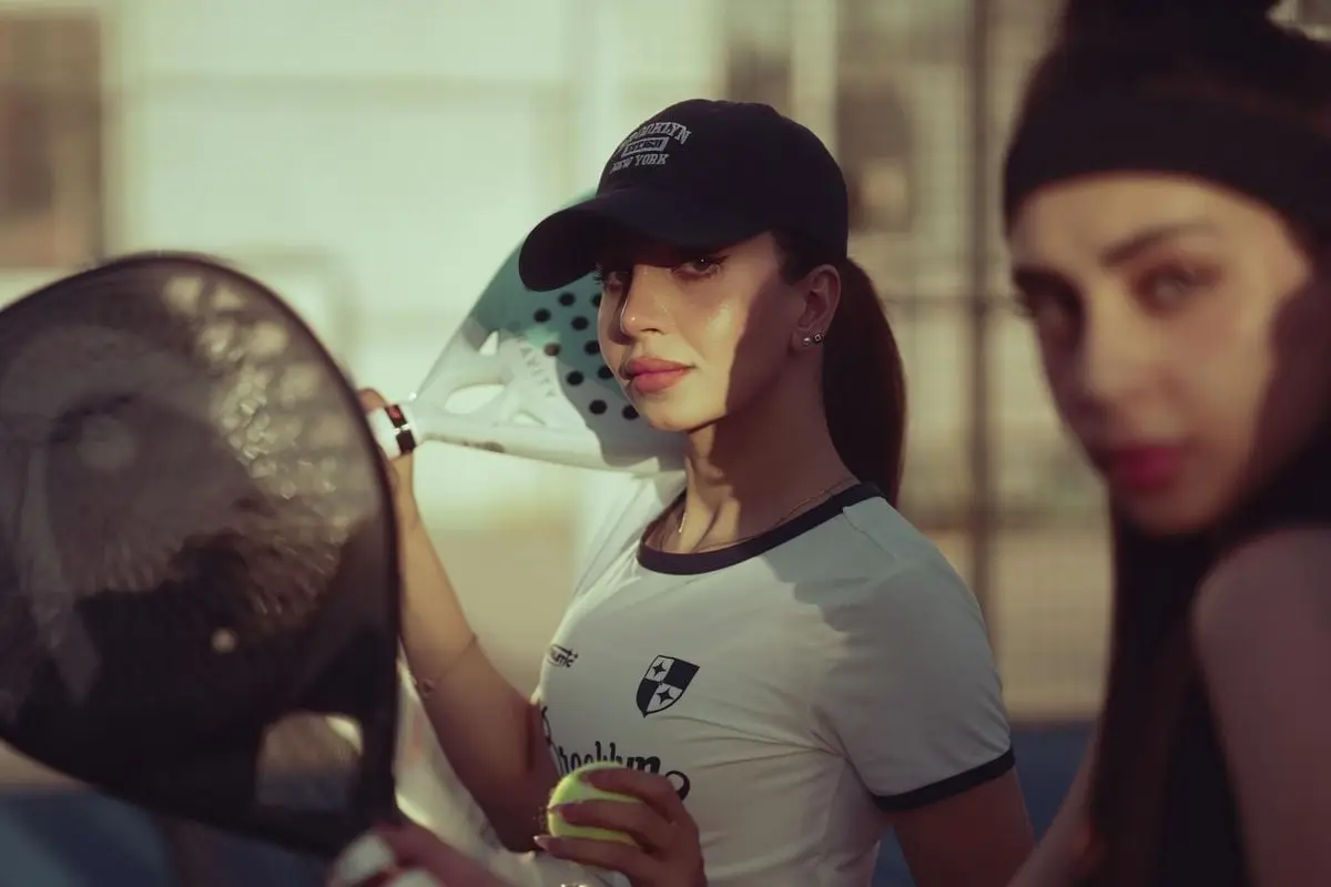 Women playing paddle tennis on an outdoor court, showcasing active sports and fitness fashion.
