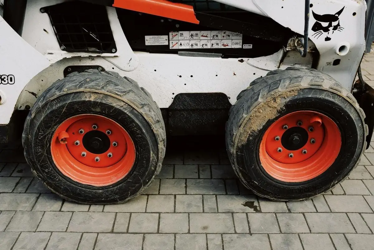 Detailed view of construction machinery wheels with red rims on a paved surface.