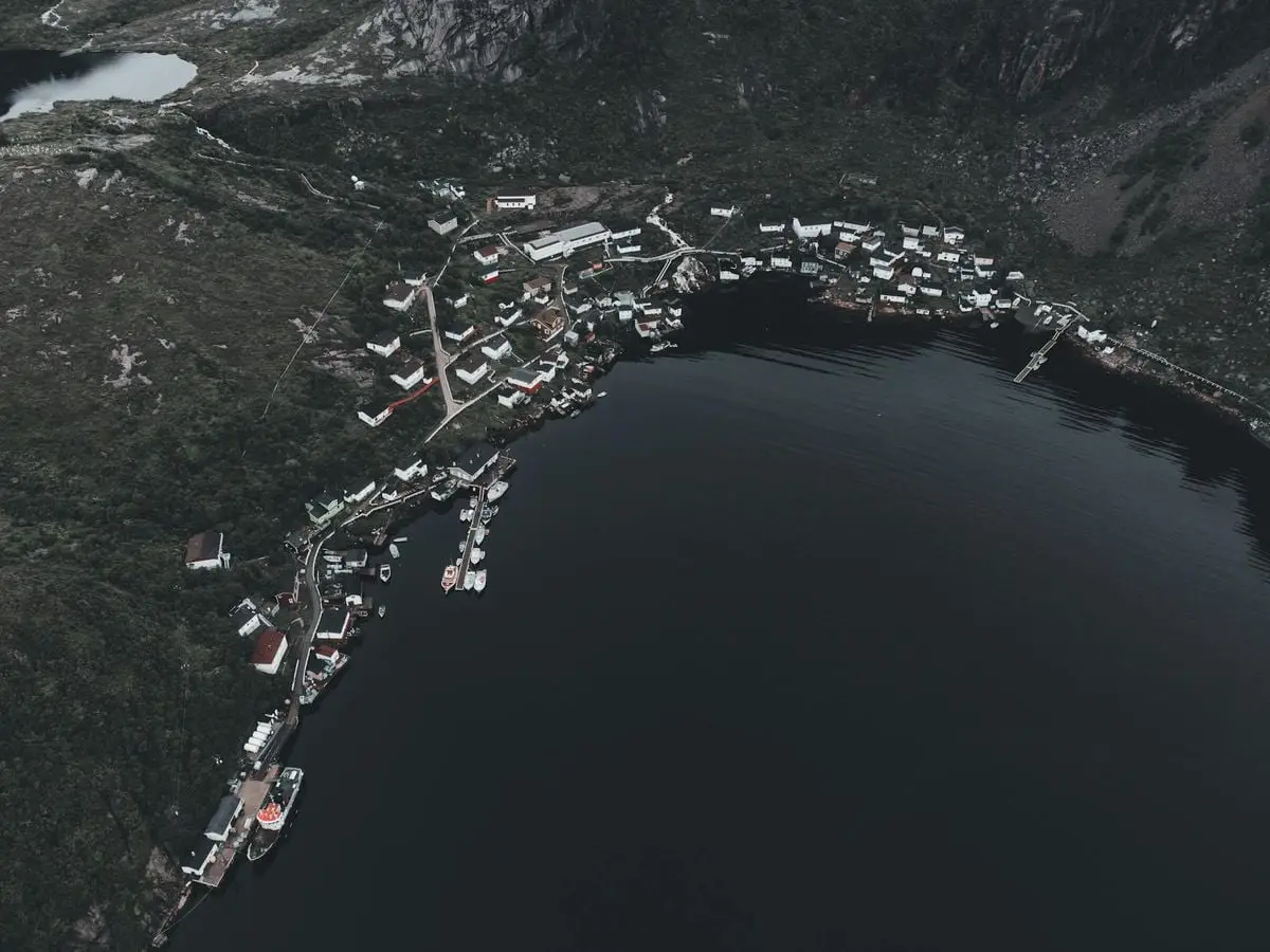 Stunning aerial shot of a small coastal town surrounded by lush hills and a serene lake.