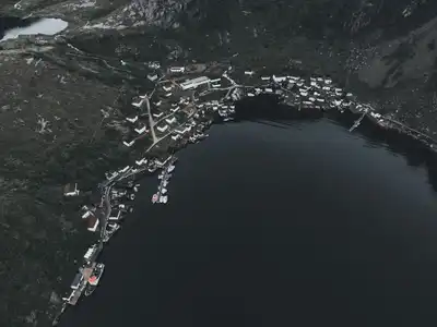 Stunning aerial shot of a small coastal town surrounded by lush hills and a serene lake.