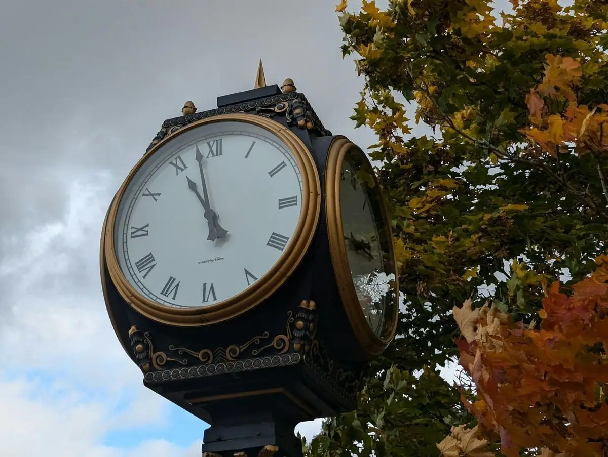 A decorative clock in Truro, Nova Scotia framed by vibrant autumn leaves.