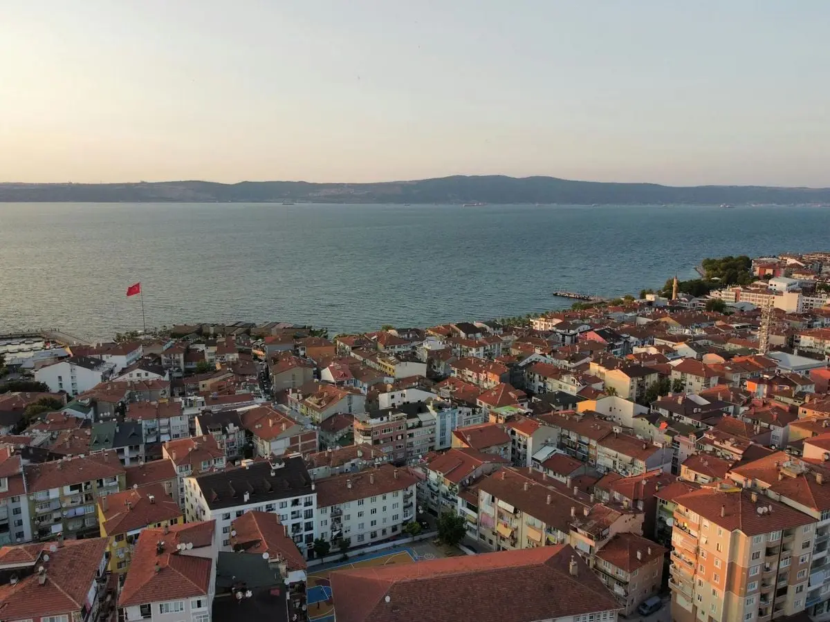 Aerial view of a coastal city with red rooftops and sea during sunset. Scenic urban landscape.