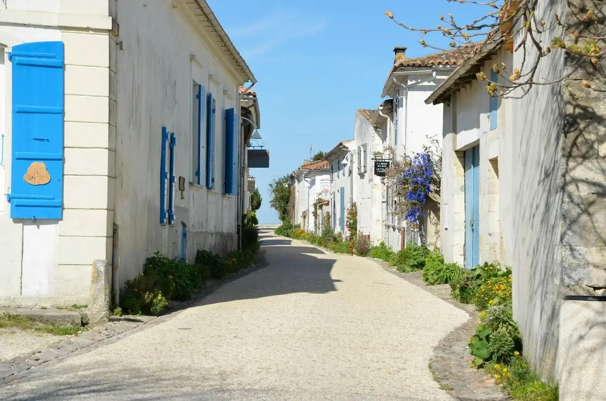 Idyllic narrow street with white houses and blue shutters in Talmont-sur-Gironde, France.