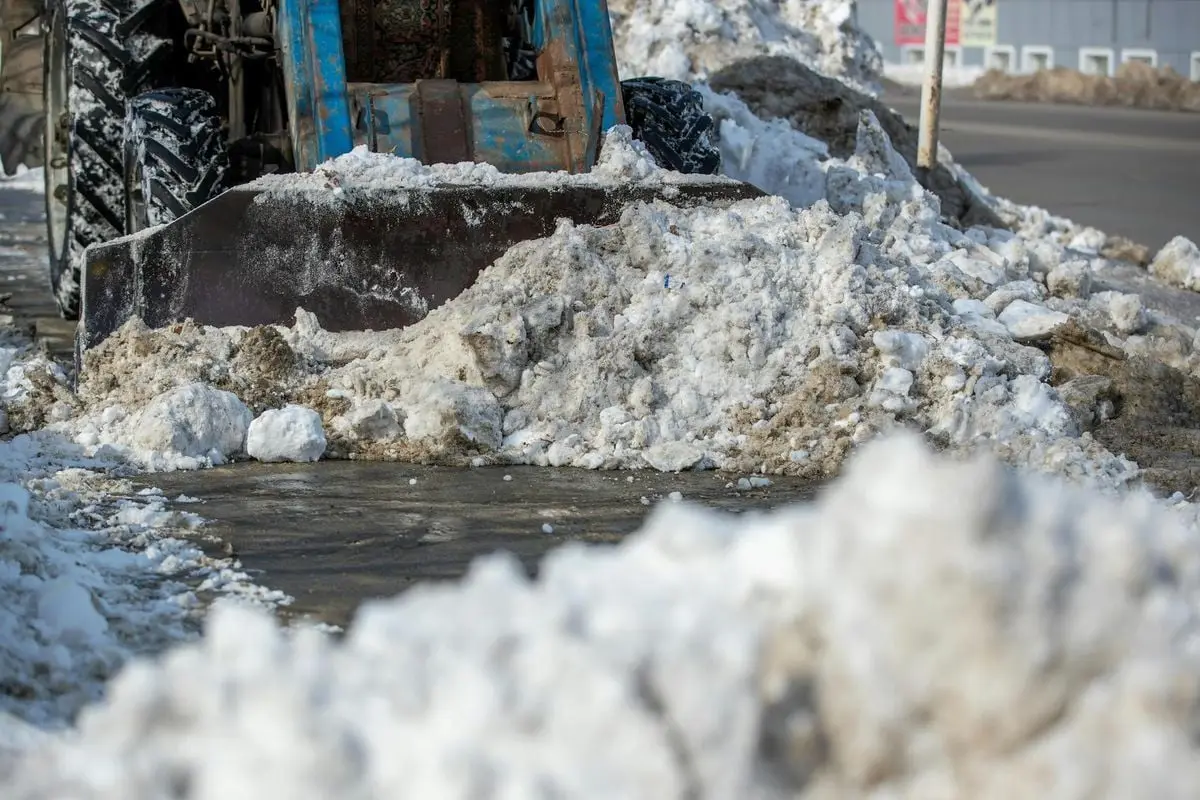 A snow plow clearing icy winter snow from a city street, showcasing winter urban maintenance.