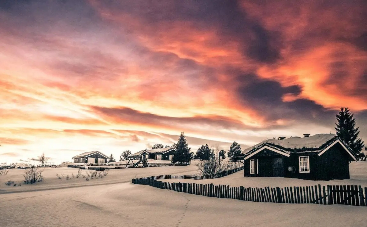 Captivating sunset over snowy village in Hol, Norway, showcasing winter beauty.