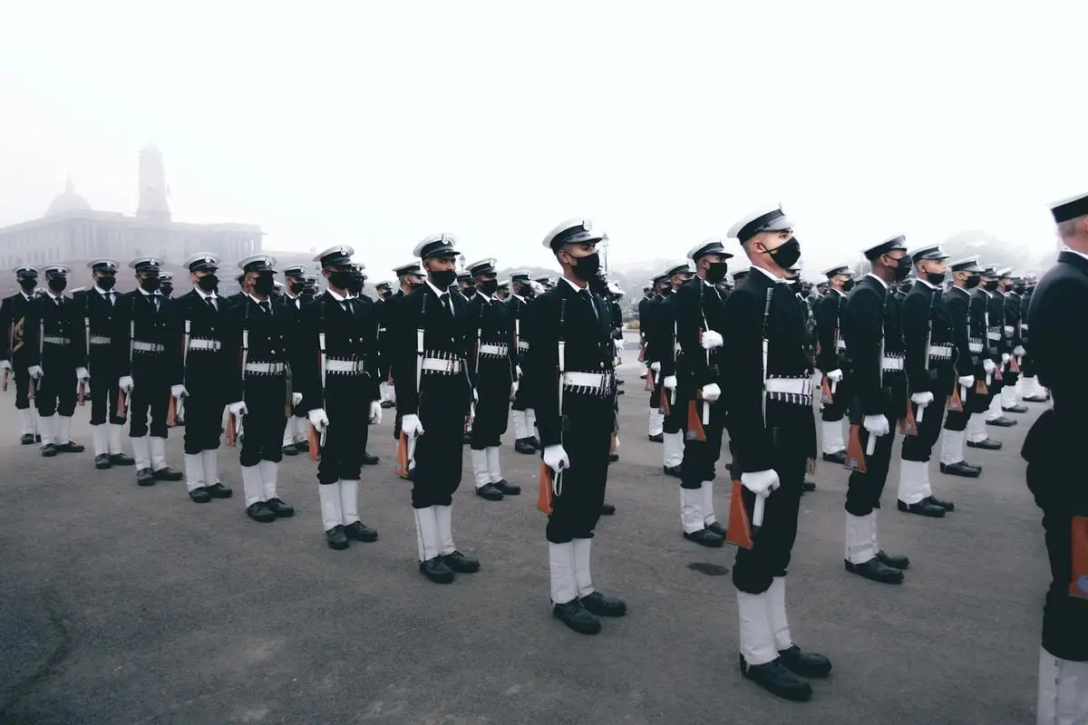 A group of soldiers standing at attention in full uniforms during a military parade in an urban setting.