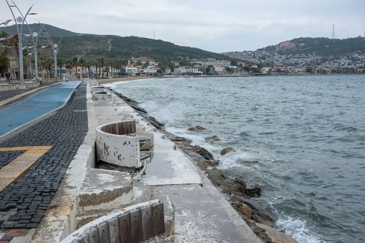 Experience the serene coastline of Foça, İzmir with its charming seashore promenade and distant hills.