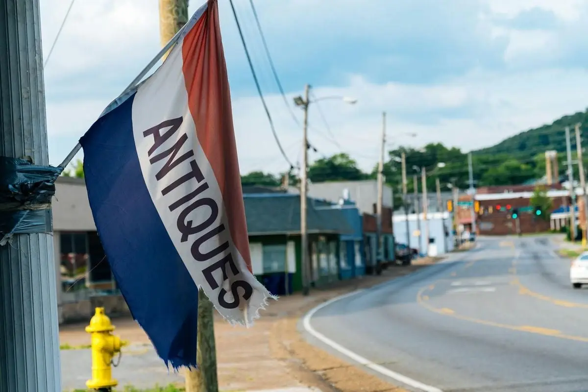 A rustic street scene with an antiques flag and empty road, capturing small-town charm.