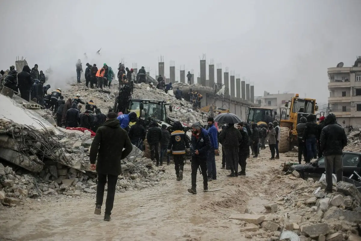 Volunteers and rescuers search through rubble after a building collapse in Idlib, Syria.