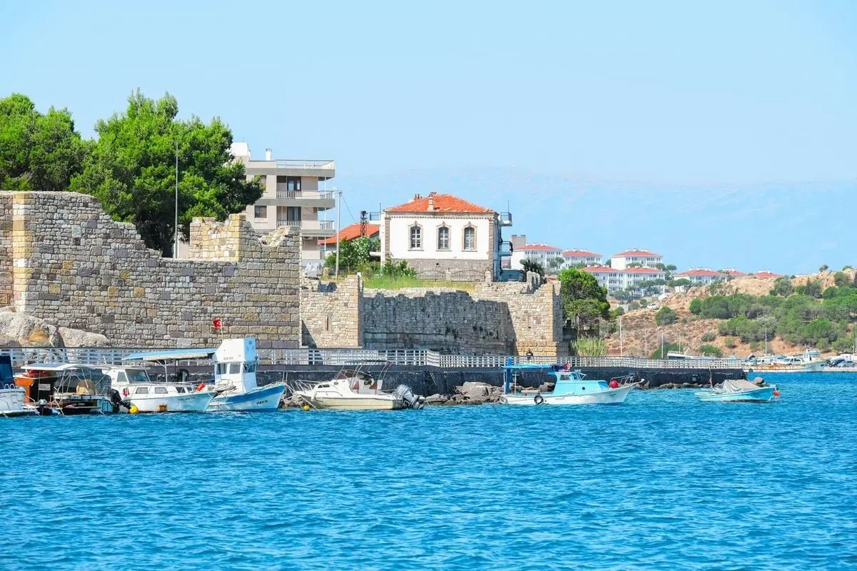 Explore the tranquil coastal beauty of Foça, İzmir with historic architecture and vibrant blue waters.