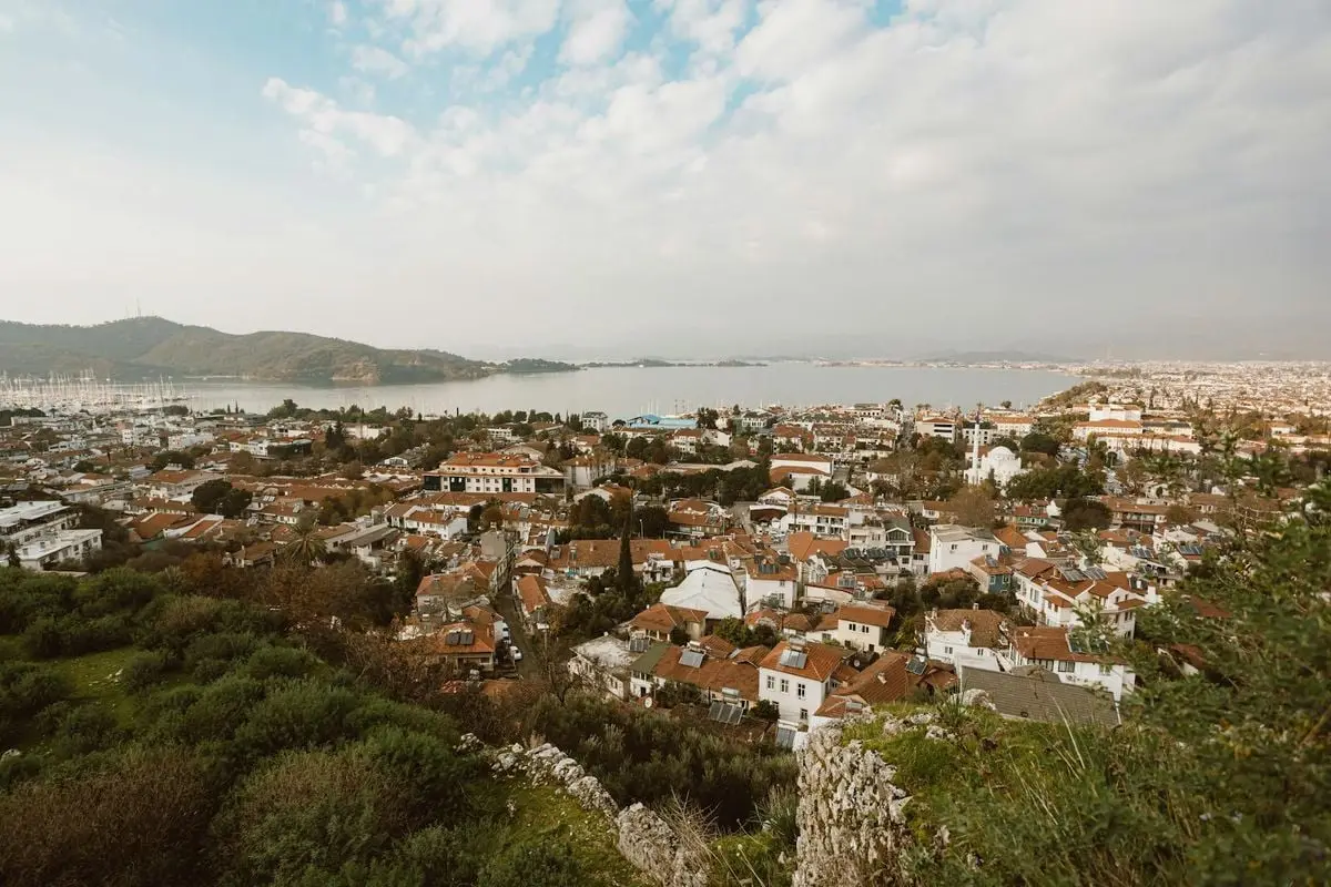 Aerial view of a beautiful coastal town surrounded by hills and water, showcasing architecture and nature.