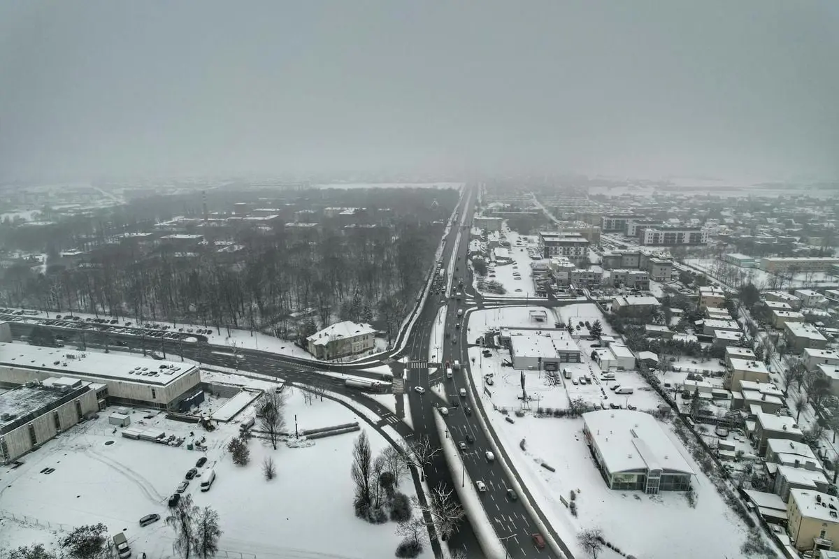 Aerial shot capturing a snow-blanketed townscape under a foggy winter sky.