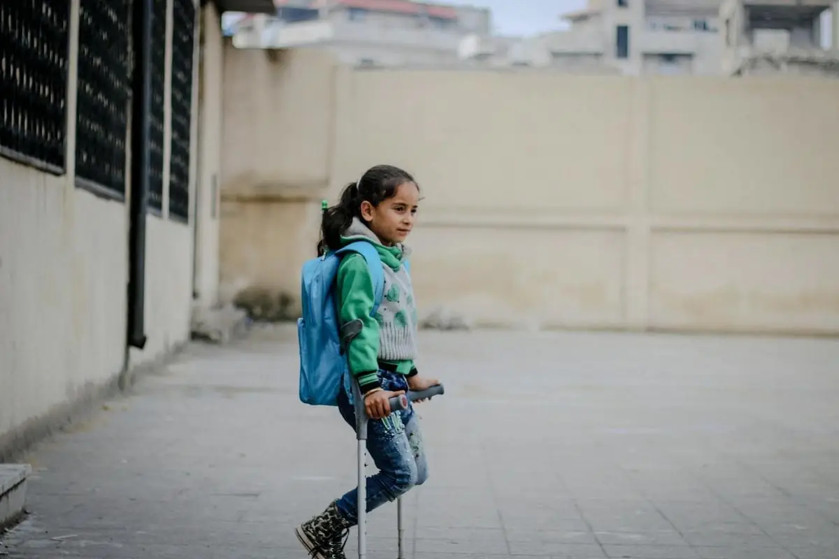 Side view of ethnic girl with backpack looking away on shabby street in daytime