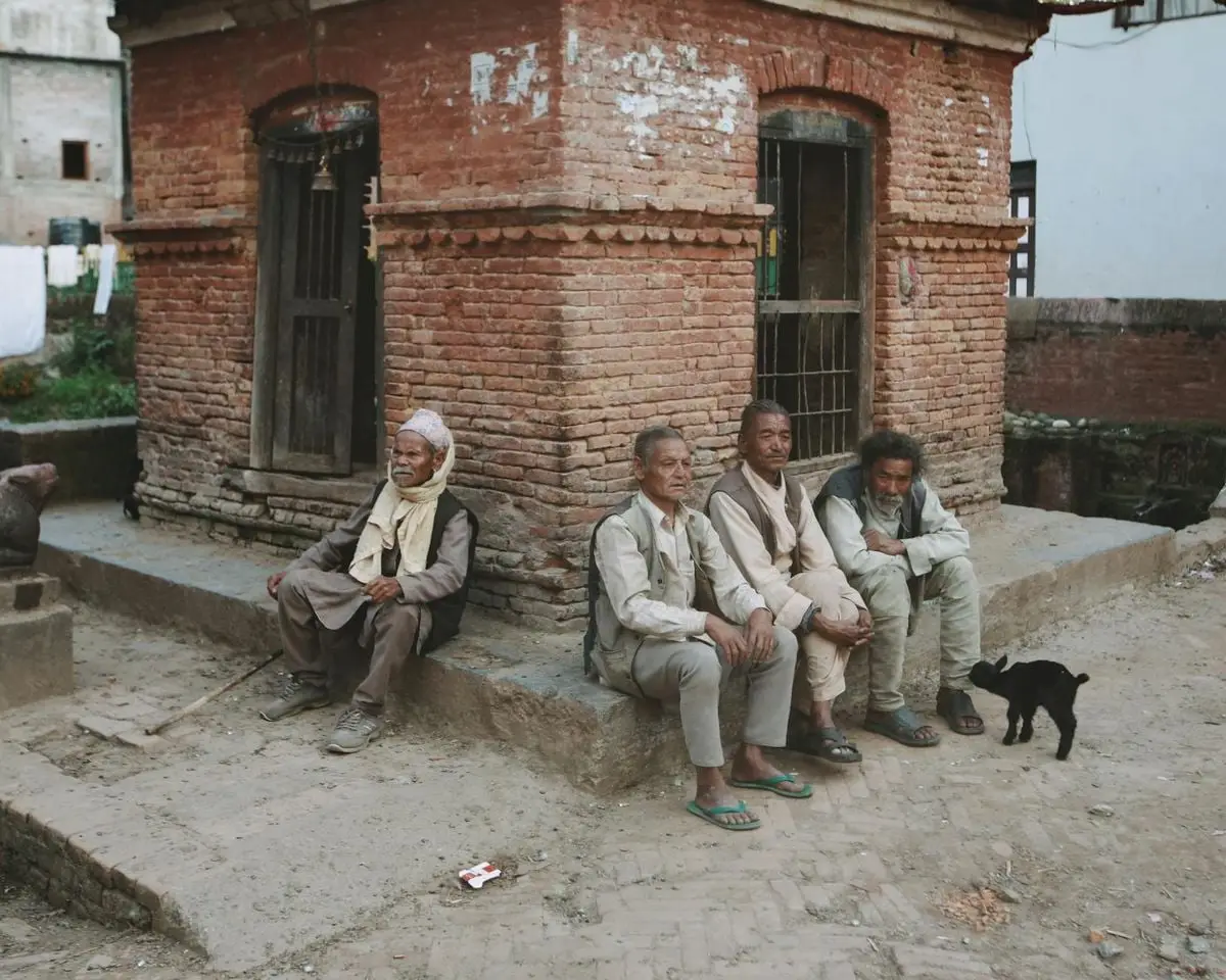 A group of elderly men sit outside a historic brick building, embodying community life.