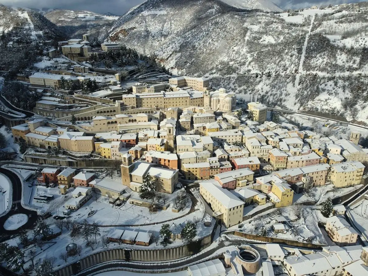 Scenic view of small remote town located in hilly terrain covered with snow on clear winter weather